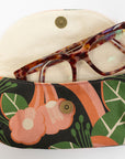 Floral-patterned eyeglass case with tortoiseshell glasses on a white background