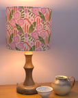 Lamp with a floral patterned shade on a wooden table with two ceramic items.