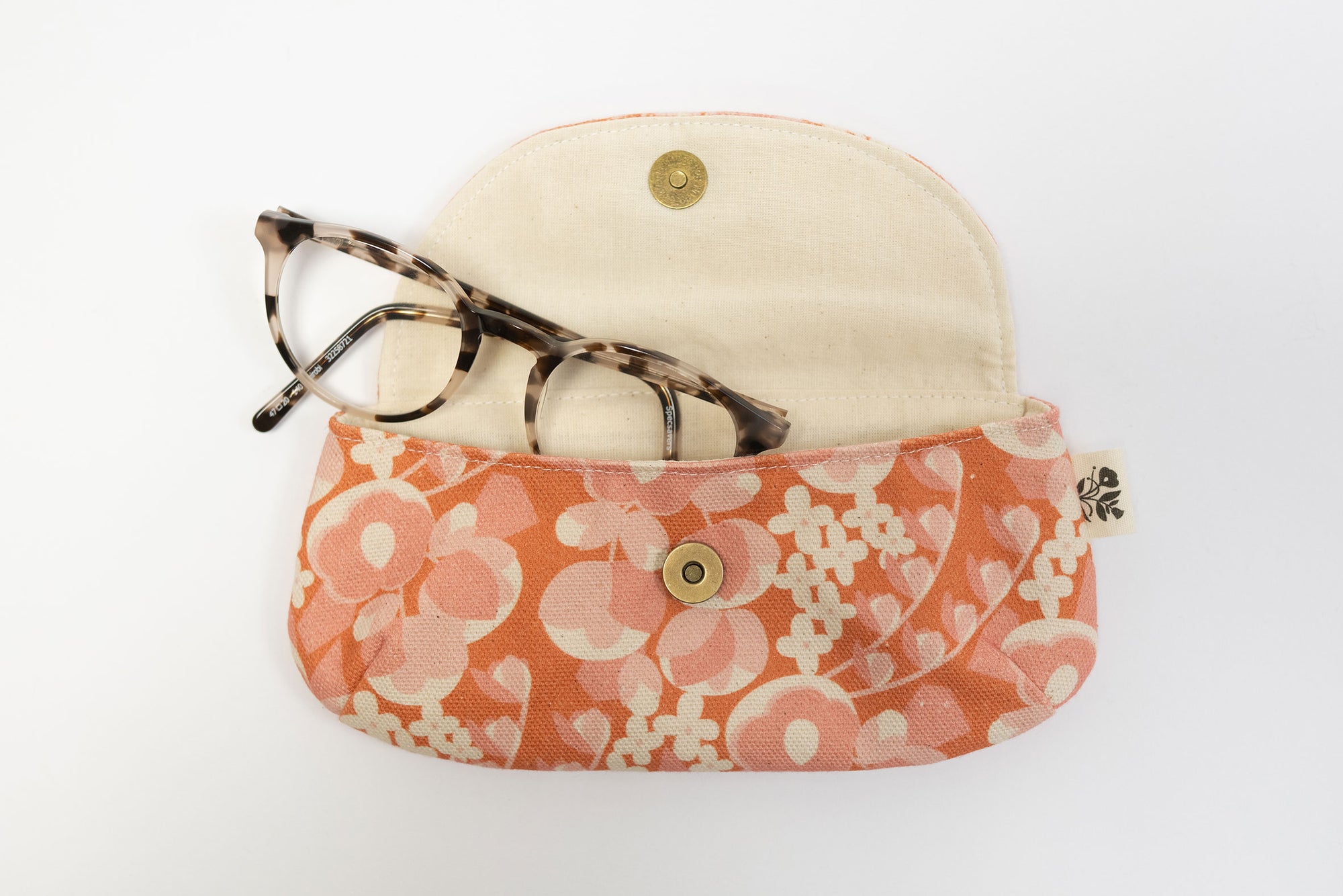 Floral-patterned eyeglass case with a beige hat on a white background