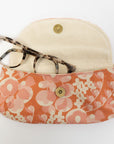 Floral-patterned eyeglass case with a beige hat on a white background