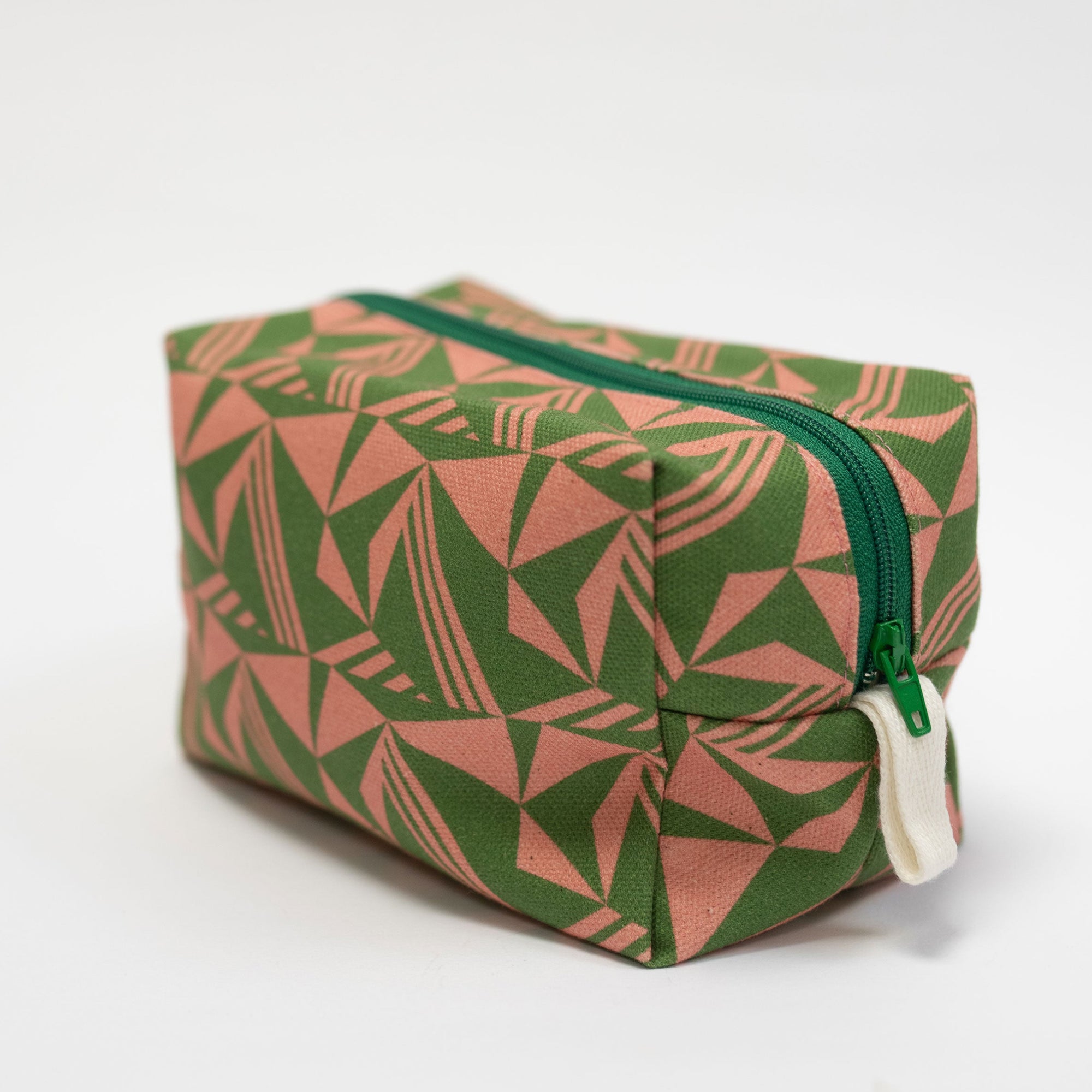Green and pink patterned toiletry bag with a green zipper on a white background