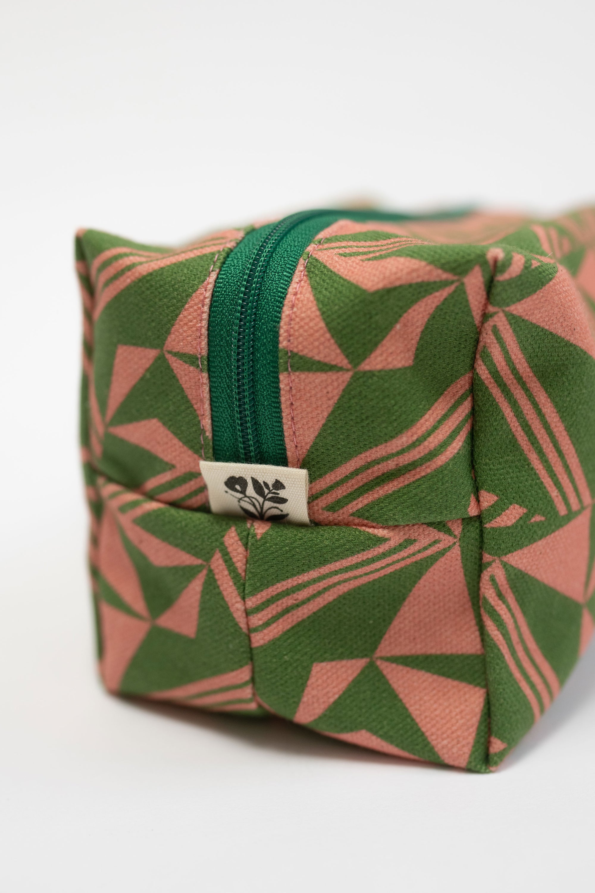 Fabric pouch with green and pink geometric pattern on a white background