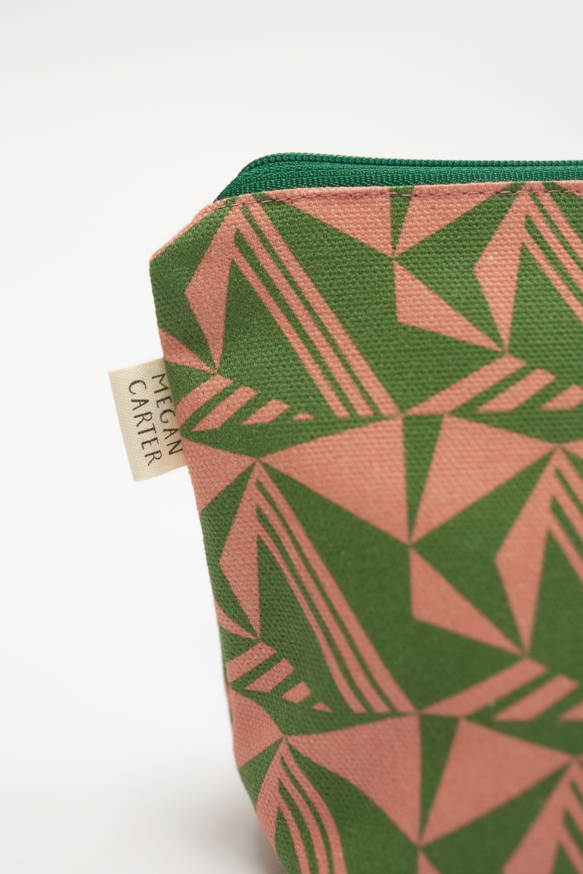 Green and pink geometric patterned pouch with a visible brand label on a white background