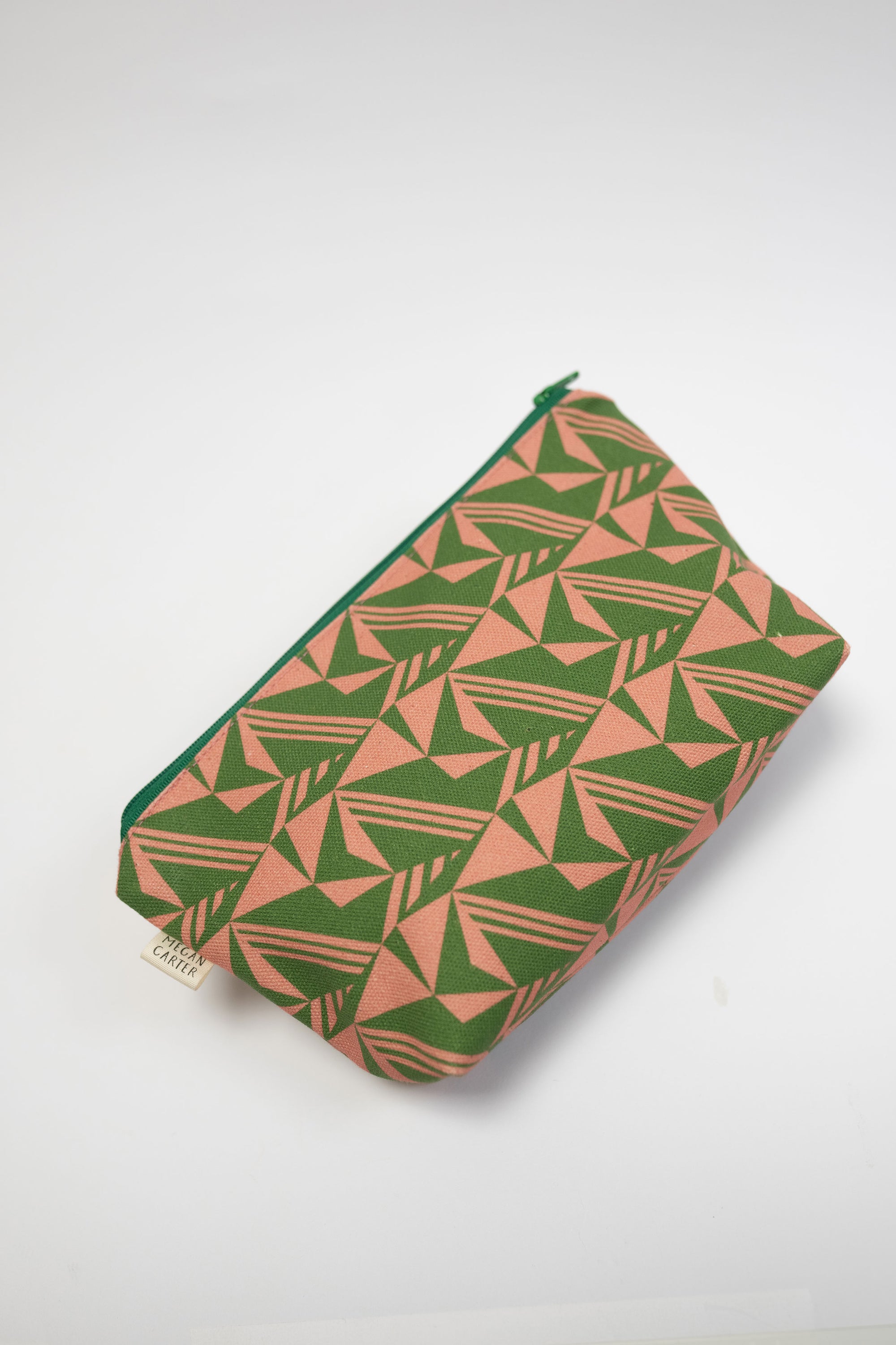 Green and pink geometric patterned pouch on a white background