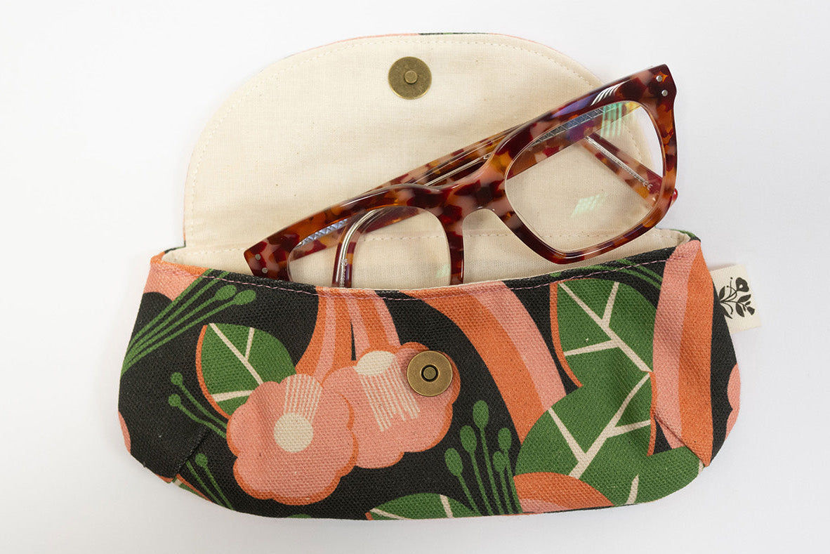 Floral-patterned eyeglass case with tortoiseshell glasses on a white background